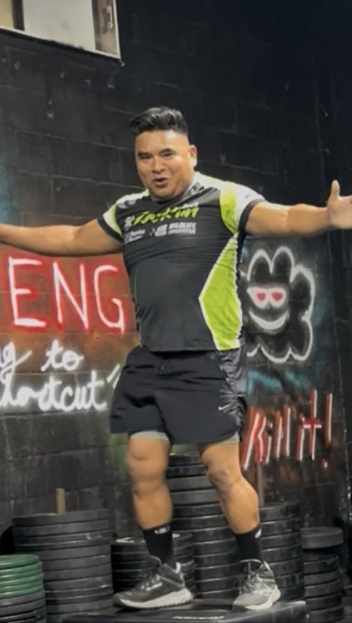 Sabino after his transformation with Máquina Strength, standing on stacked weight plates